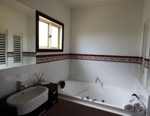 Baño blanco con bañera y lavamanos en Snowy river homestead, 