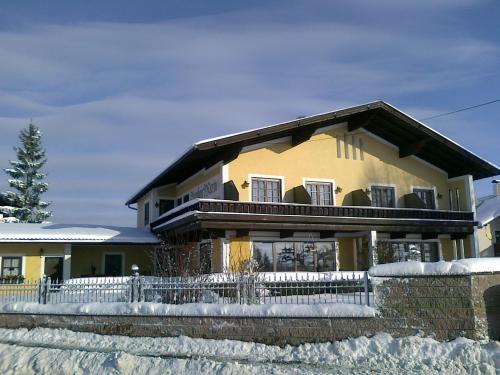 a yellow house with a fence in the snow at Haus Maria Holzöster in Franking