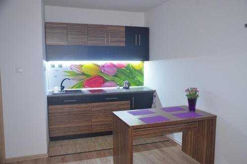 a kitchen with a table and a painting on the wall at Apartament Masovia in Mrągowo