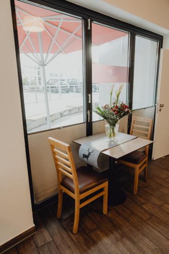 a table and chairs with a vase of flowers on it at Stadt Land Fluss New Apartments by Zollhaus in Forchheim