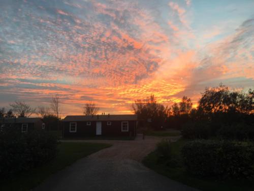 a sunset over a house in a yard at Resort Land & Zee in Scharendijke