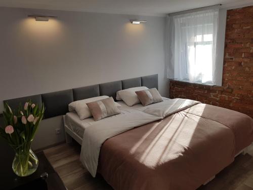 un grand lit dans une chambre avec un mur de briques dans l'établissement IZERSKA ZATOKA, à Stara Kamienica