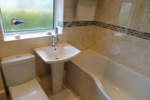 a bathroom with a sink and a toilet and a tub at Beautiful family getaway, close to the beach in Fairbourne