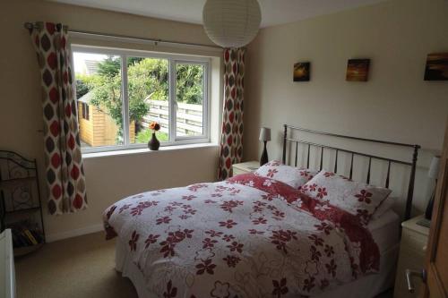 a bedroom with a red and white bed with a window at Beautiful family getaway, close to the beach in Fairbourne