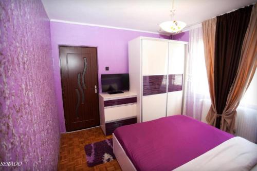 百樂費利克斯的住宿－Apartamente DELUXE Serado，紫色卧室配有一张床和电视