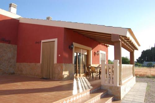 una casa rossa con portico e tavolo di Alojamientos Casa Ruiz ad Archivel