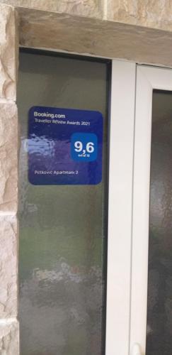 a window with a blue sign on the side of a building at Petkovic Apartmani 2 in Tivat