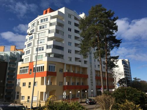 un edificio blanco alto con un árbol delante de él en Wolin-Travel Apartamenty Statek z widokiem na morze en Międzyzdroje