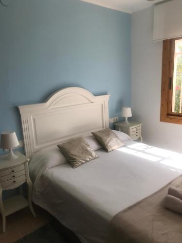 a bedroom with a large white bed with two tables at Amazing in front of the sea apartment in Comarruga