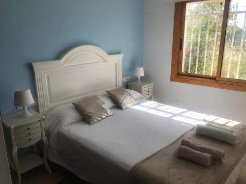 a bedroom with a white bed and a window at Amazing in front of the sea apartment in Comarruga