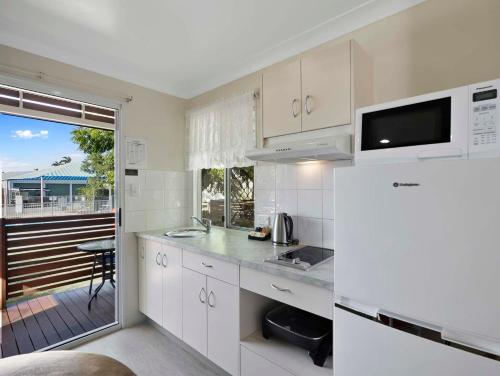 a kitchen with white cabinets and a view of a deck at Queens Beach Tourist Village in Bowen