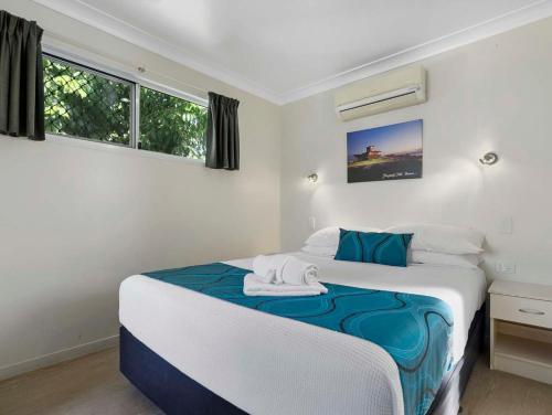 a bedroom with a bed with blue and white sheets at Queens Beach Tourist Village in Bowen