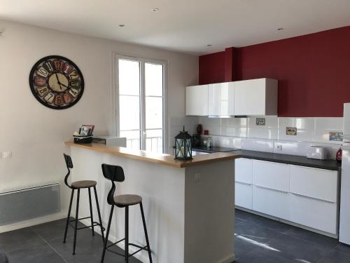 una cocina con 2 taburetes y un reloj en la pared en Jolie maison en tuffeau dans le centre de Saumur, en Saumur