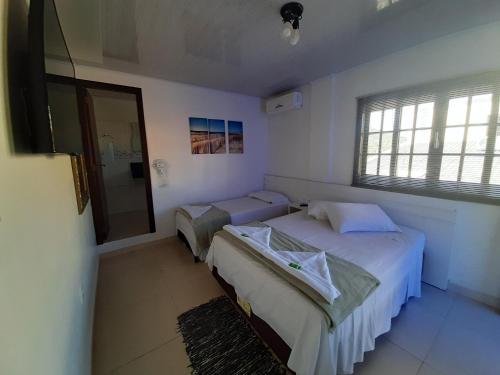 um quarto com 2 camas individuais e uma janela em Pousada Casa do Luiggi em Penha