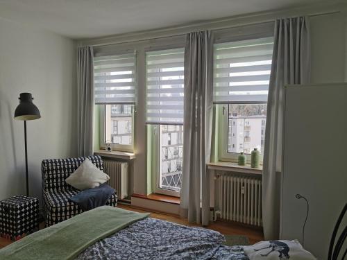 Schlafzimmer mit einem Bett, einem Stuhl und Fenstern in der Unterkunft Die Birke in Bremen