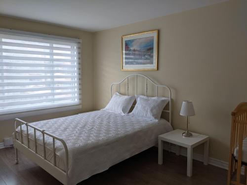 1 dormitorio con cama blanca y ventana en 3 BDR appartement,WiFI,Netflix free parking en Montreal