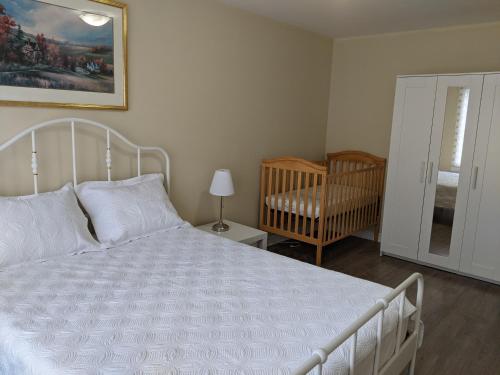a bedroom with a white bed and a crib at 3 BDR appartement,WiFI,Netflix free parking in Montreal
