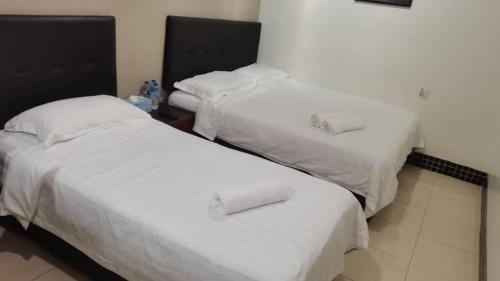 2 camas en una habitación de hotel con sábanas blancas en LSN Hotel (KL) Sdn Bhd en Kuala Lumpur