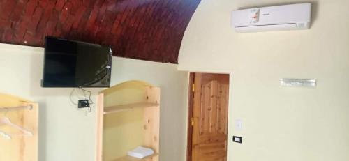 a room with a tv on the wall and a door at Ahmed Safari Camp in Bawiti