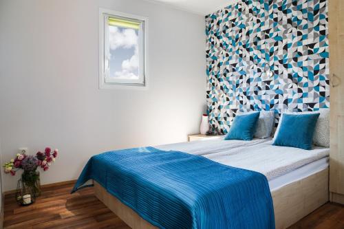 a bedroom with a bed with a blue blanket on it at Domki Bungalow Stella Resort & SPA in Władysławowo