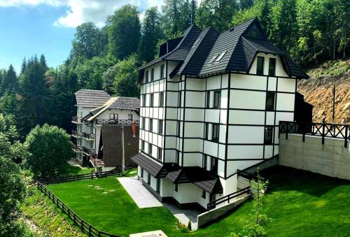 una gran casa blanca con techo negro en Vila Irina Kopaonik - Apartman IN, en Kopaonik
