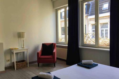 1 dormitorio con 1 cama, 1 silla y ventanas en Spacious Duplex + Terrace in Ghent. Top Location!, en Gante