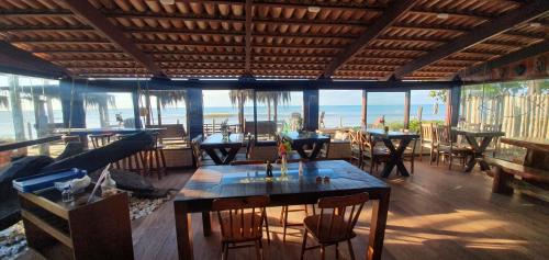 restauracja ze stołami i krzesłami oraz widokiem na ocean w obiekcie Hospedaria Rosa dos Ventos w mieście Marataízes