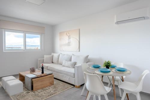 a living room with a white couch and a table at COSTA VASIA Seaside Suites and Apartments in Vrahati
