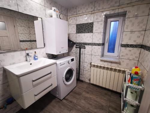 ein Badezimmer mit einer Waschmaschine und einem Waschbecken in der Unterkunft Zielona Chałupa in Tuchorza Nowa