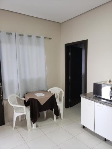 a kitchen with a table and two chairs and a microwave at Flat Genoveva in Tangara da Serra