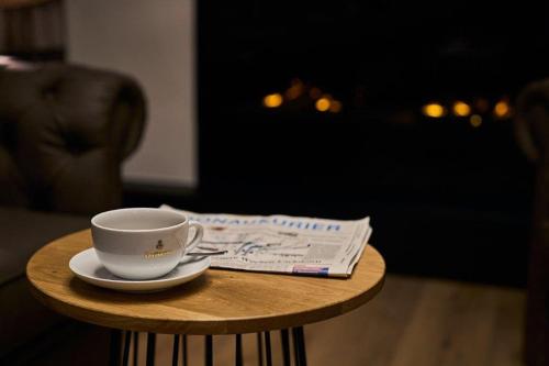 a cup of coffee on a table with a newspaper at Zum Dallmayr Hotel Garni in Berching