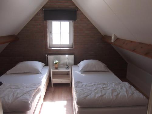 2 bedden in een zolderkamer met een raam bij Vakantiehuisje gelegen op een kattensprong van Veerse Meer en Noordzee! in Kamperland