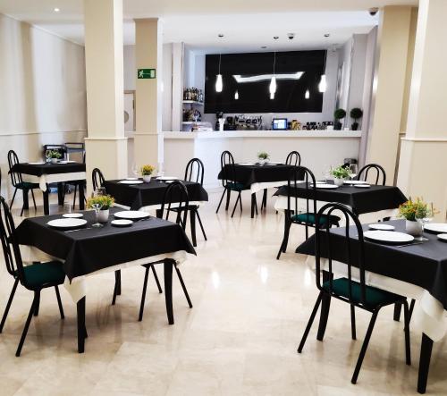 a restaurant with black tables and chairs and a kitchen at Hotel Ciudad de Navalcarnero in Navalcarnero