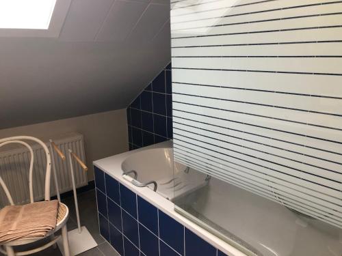 a bathroom with a tub and a chair and blue tiles at vieux colombier in Tournai