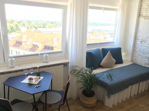 ein Wohnzimmer mit einem Sofa, einem Tisch und einem Fenster in der Unterkunft Liebevoll renoviertes Apartment mit Panoramablick in Friedrichshafen