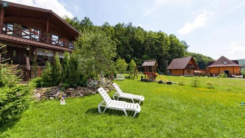 a yard with two white chairs and a playground at Chalet Vedmezhe in Polyana