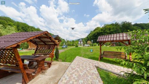 two wooden benches and a gazebo in a yard at Chalet Vedmezhe in Polyana