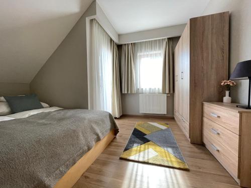 a bedroom with a bed and a rug on the floor at Panoráma Apartmanház in Balatonfüred