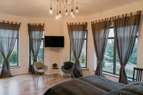 1 dormitorio con ventanas, 1 cama y sillas en Valet Apartment en Mārupe