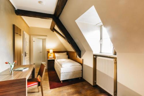a room with a bed and a desk and a window at Amtshaus Freinsheim in Freinsheim