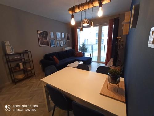 uma sala de estar com uma mesa e um sofá em Nowoczesny Apartament przy Manufakturze z parkingiem podziemnym i klimatyzacją em Łódź