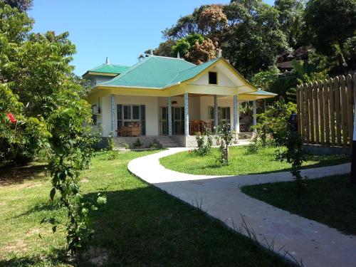 a yellow house with a green roof at Zanboza Guesthouse in La Digue
