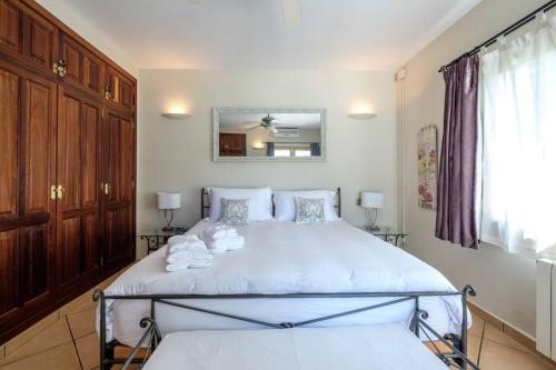 a bedroom with a bed with white sheets and a mirror at Nice villa Marpessa in Portals Nous with pool in Portals Nous