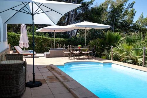 a swimming pool with umbrellas and a table and chairs at Nice villa Marpessa in Portals Nous with pool in Portals Nous