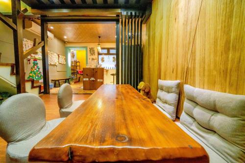 une grande table en bois dans une pièce avec des chaises dans l'établissement Lazy Cat, à Luodong