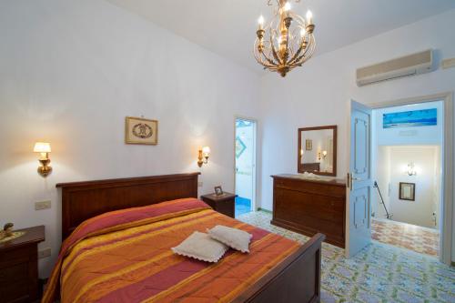 una camera con letto, specchio e lampadario a braccio di Casa Aurelia a Praiano