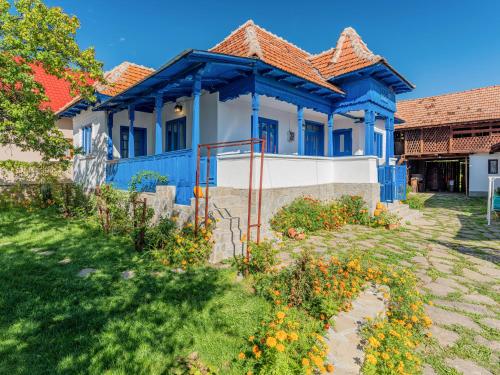 a blue and white house with flowers in the yard at Casa de vacanta traditionala romaneasca in Schiuleşti