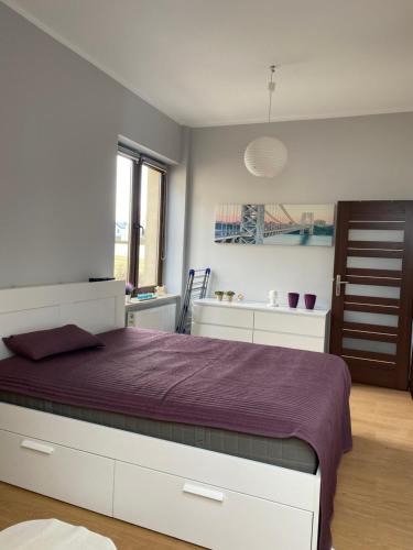 sypialnia z dużym łóżkiem i fioletowym kocem w obiekcie Lipowa w mieście Modlnica