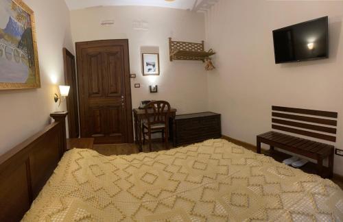 a bedroom with a bed and a television and a chair at Hotel Mangalemi in Berat