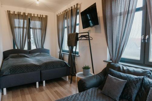 a bedroom with a bed and a couch and windows at Valet Apartment in Mārupe